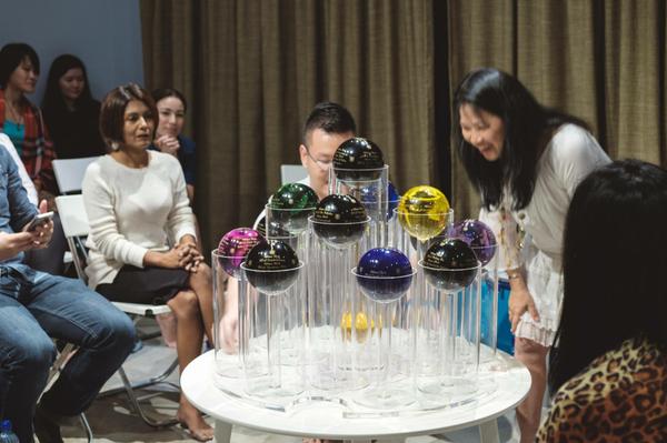 A Saturn Bubbler, its jewel-coloured spheres gathered around by a circle of people